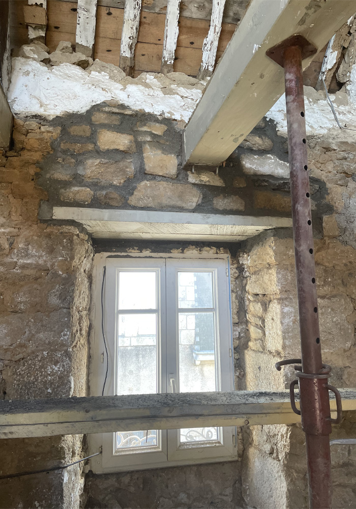 Rénovation d'un mur d'immeuble en pierres et pose de poutre