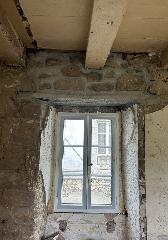 Rénovation d'un mur d'immeuble en pierres et pose de poutre. Avec plafond